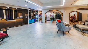 A spacious lobby with a reception desk, seating area, and a bar. - Hotel Indigo Spring - Woodlands Area by IHG (Spring)