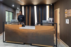 A reception desk with a wooden finish, a laptop on it, and a framed picture on the wall.