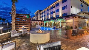 A hotel courtyard with a pool, outdoor seating, and a fire pit. - Hotel Indigo Spring - Woodlands Area by IHG (Spring)