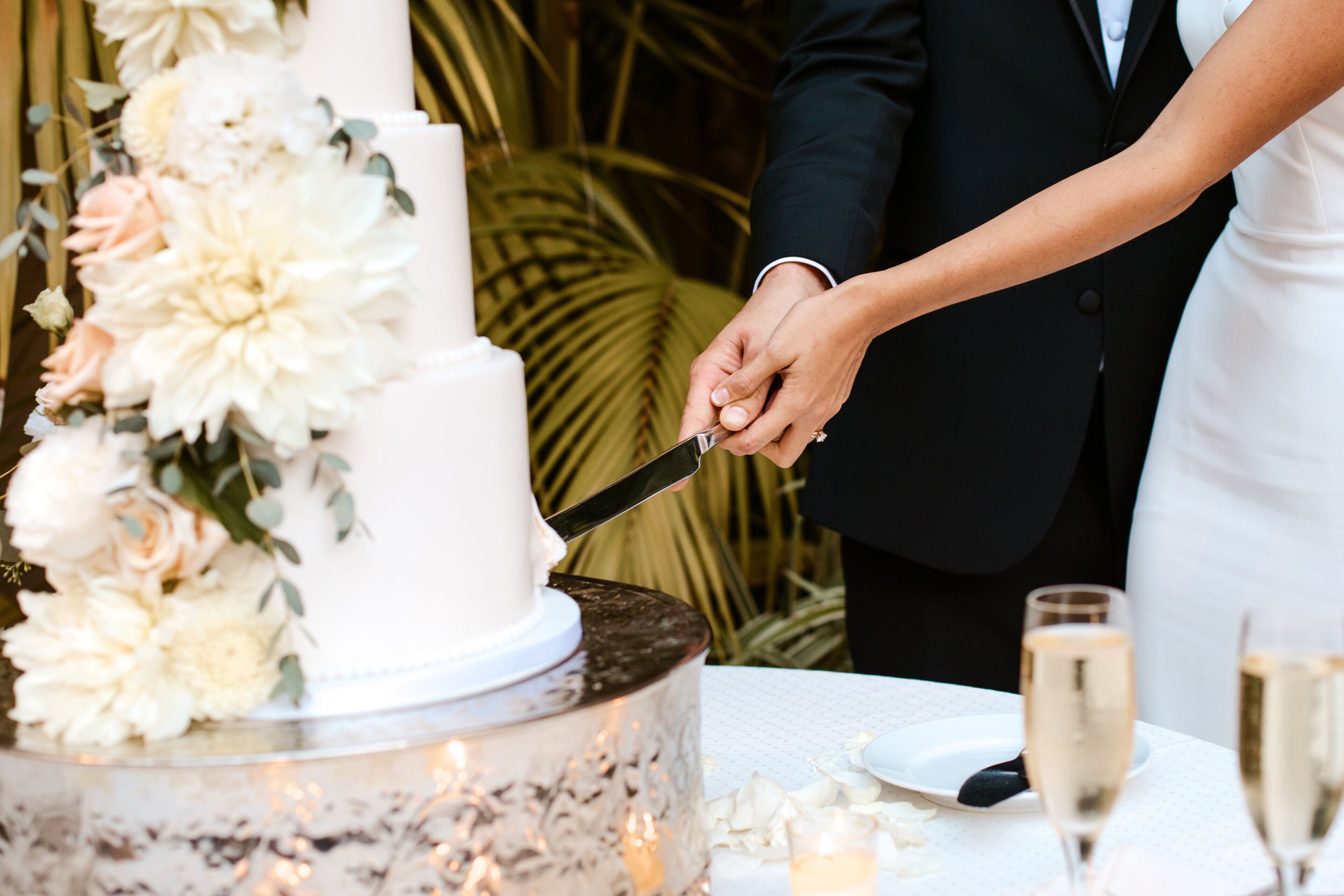 Una torta nuziale con decorazioni floreali e una coppia che la taglia.