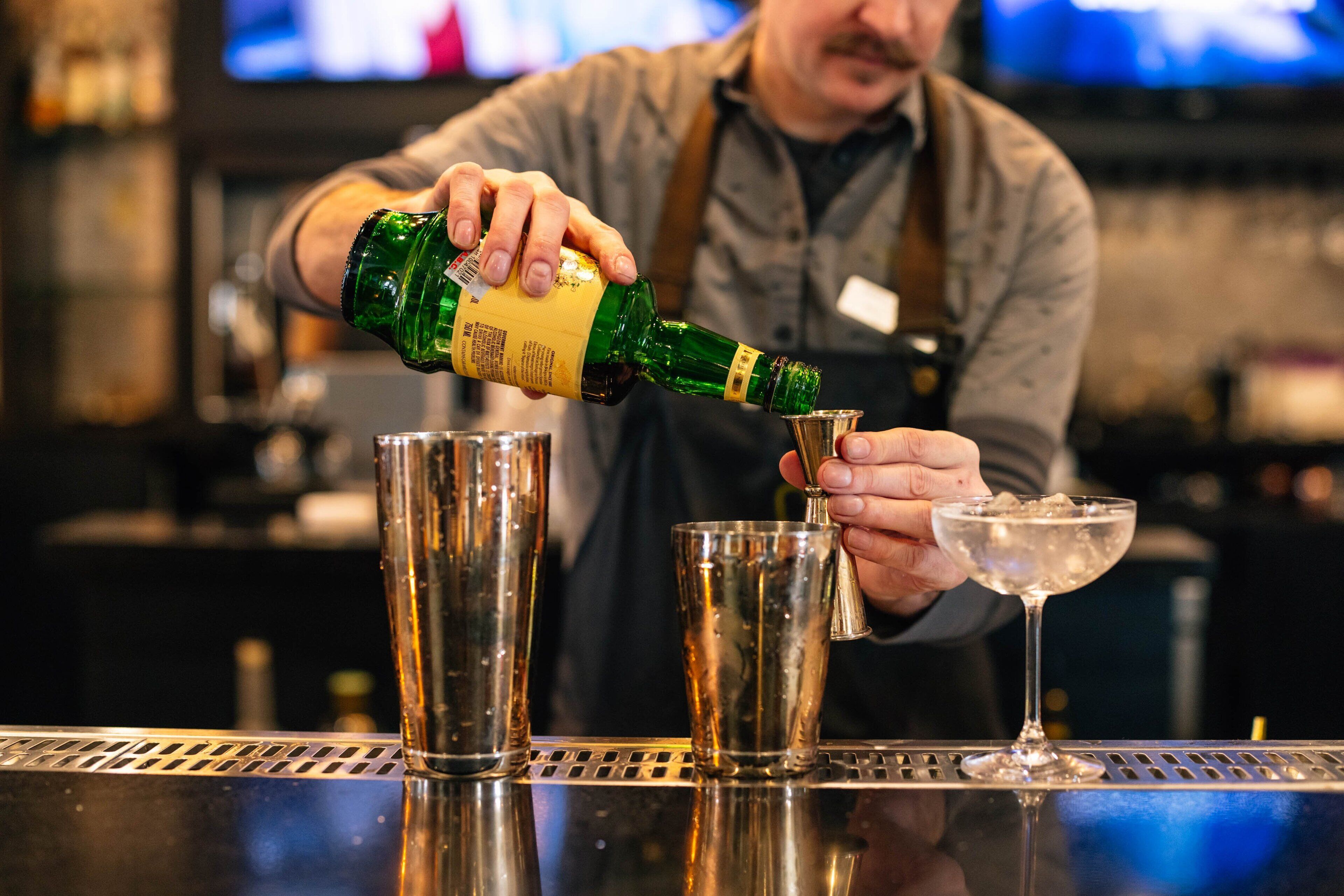 Ein Barkeeper gießt ein Getränk ein.