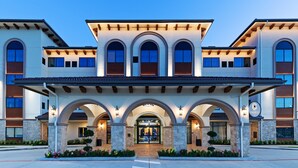 A modern hotel with a central entrance, arched walkways, and a covered patio area. - Hotel Indigo Spring - Woodlands Area by IHG (Spring)