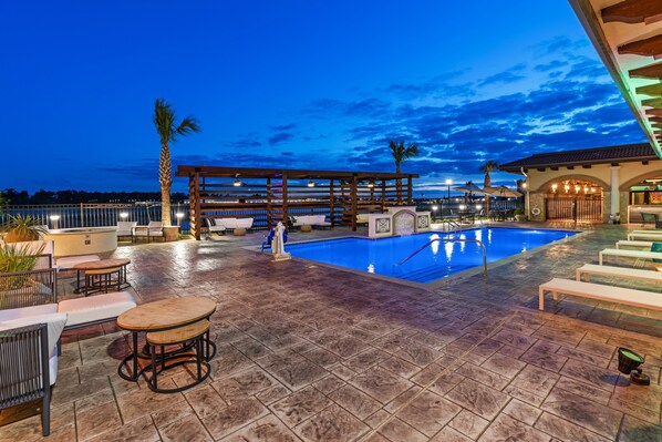 A rooftop pool area with lounge chairs, a wooden pergola, and a pool.