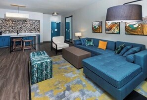 A modern living room with a blue sofa, a coffee table, and a patterned rug. - Hotel Indigo Spring - Woodlands Area by IHG (Spring)