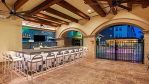 A bar area with a tiled floor, bar stools, and a counter with a television. - Hotel Indigo Spring - Woodlands Area by IHG (Spring)