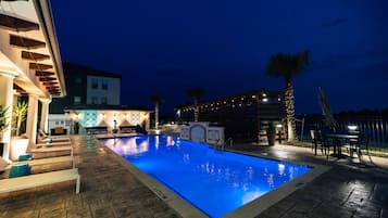 A swimming pool with a tiled deck, lounge chairs, and a palm tree.