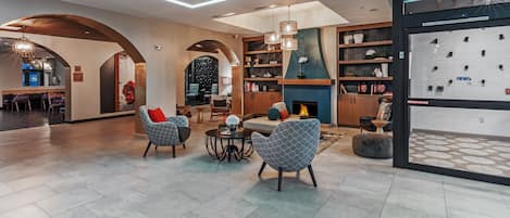 A spacious living area with modern furniture, a fireplace, and a large window overlooking the interior.