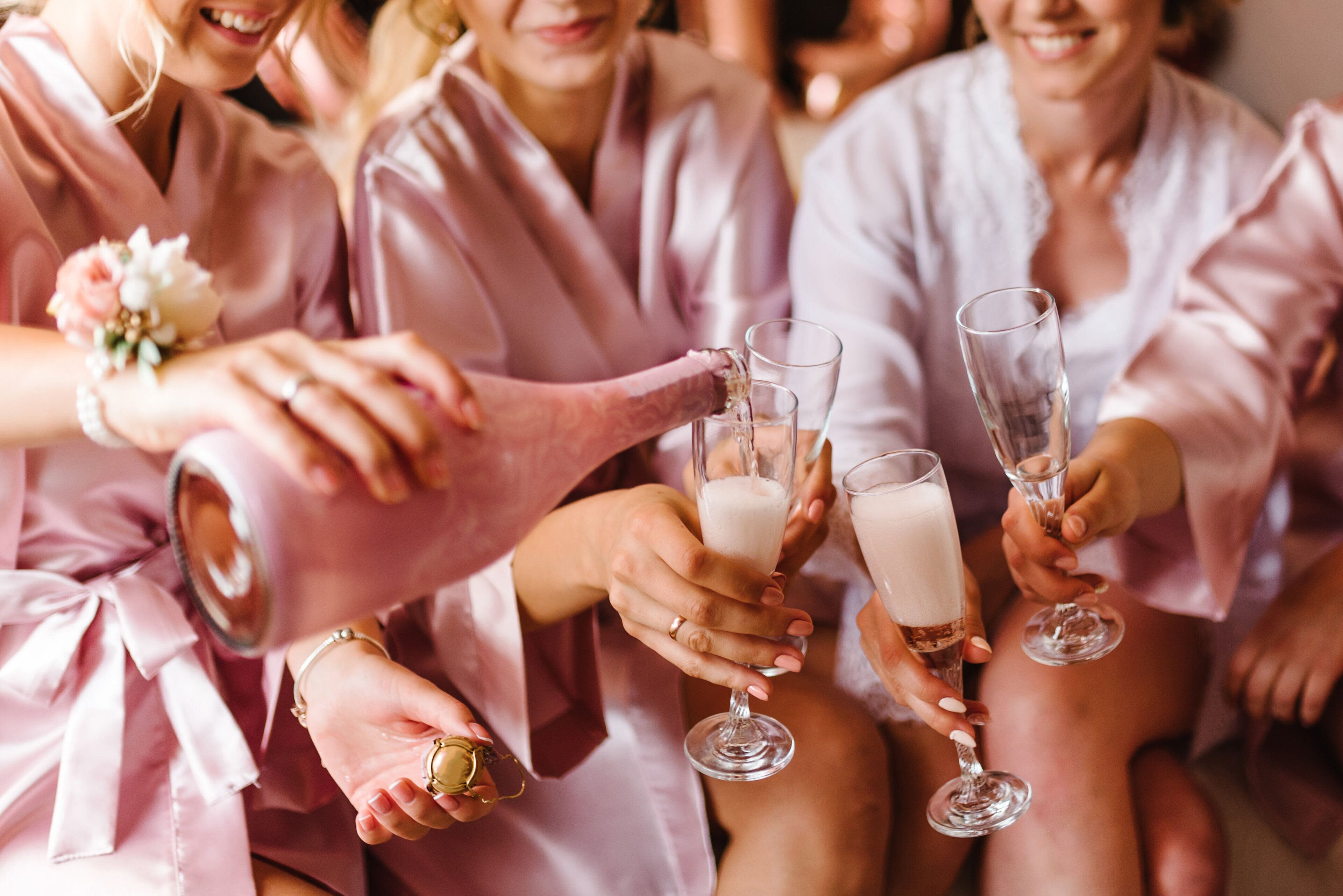 A group of people in pink robes holding champagne glasses.