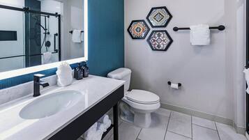 A modern bathroom with a large mirror, a sink, a toilet, and a shower area.