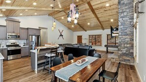 A spacious kitchen with modern appliances, a dining area with a wooden table, and a stone fireplace.