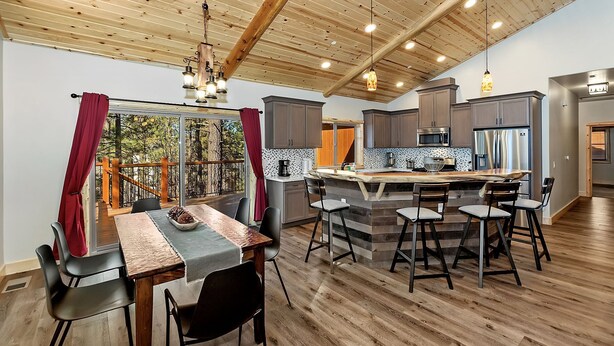 A spacious kitchen with a central island, wooden ceiling, and a view of the outdoors.