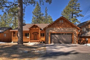 A log cabin with a stone foundation, a front porch, and a garage.