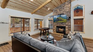 A spacious living room with a stone fireplace, large windows, and a cozy seating area.