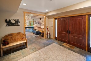 A hallway with a wooden bench, a rug, and a large wooden door.