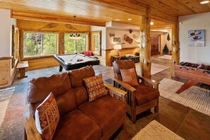 Una sala de estar acogedora con mesa de billar, sofás de cuero y techo de madera.