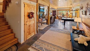 A wooden interior with a fireplace, a pool table, and a cozy seating area.