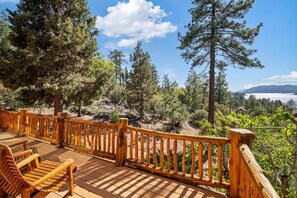 A wooden deck with a railing overlooking a forested area and a body of water.