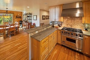A kitchen with wooden cabinets, a granite countertop, and a stainless steel stove. - Log Styling with Spectacular Lake Views! HOT TUB! Wall to Wall Game Room! (Big Bear Lake)