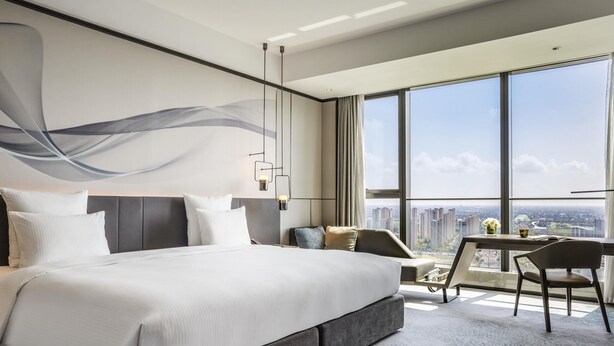 Una habitación de hotel moderna con una cama grande, un escritorio y vistas a la ciudad.