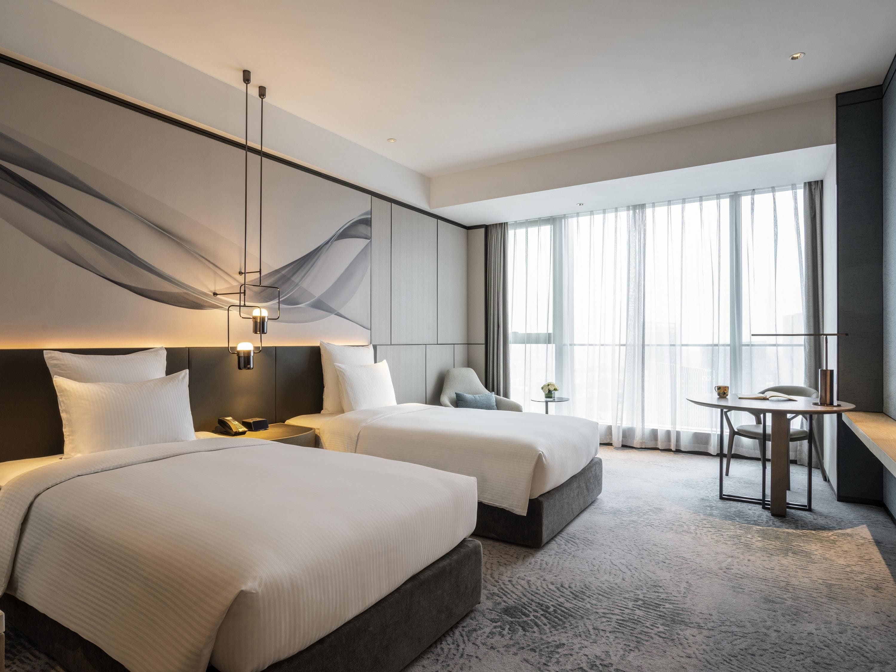 Una habitación de hotel con dos camas, una mesita y una silla.