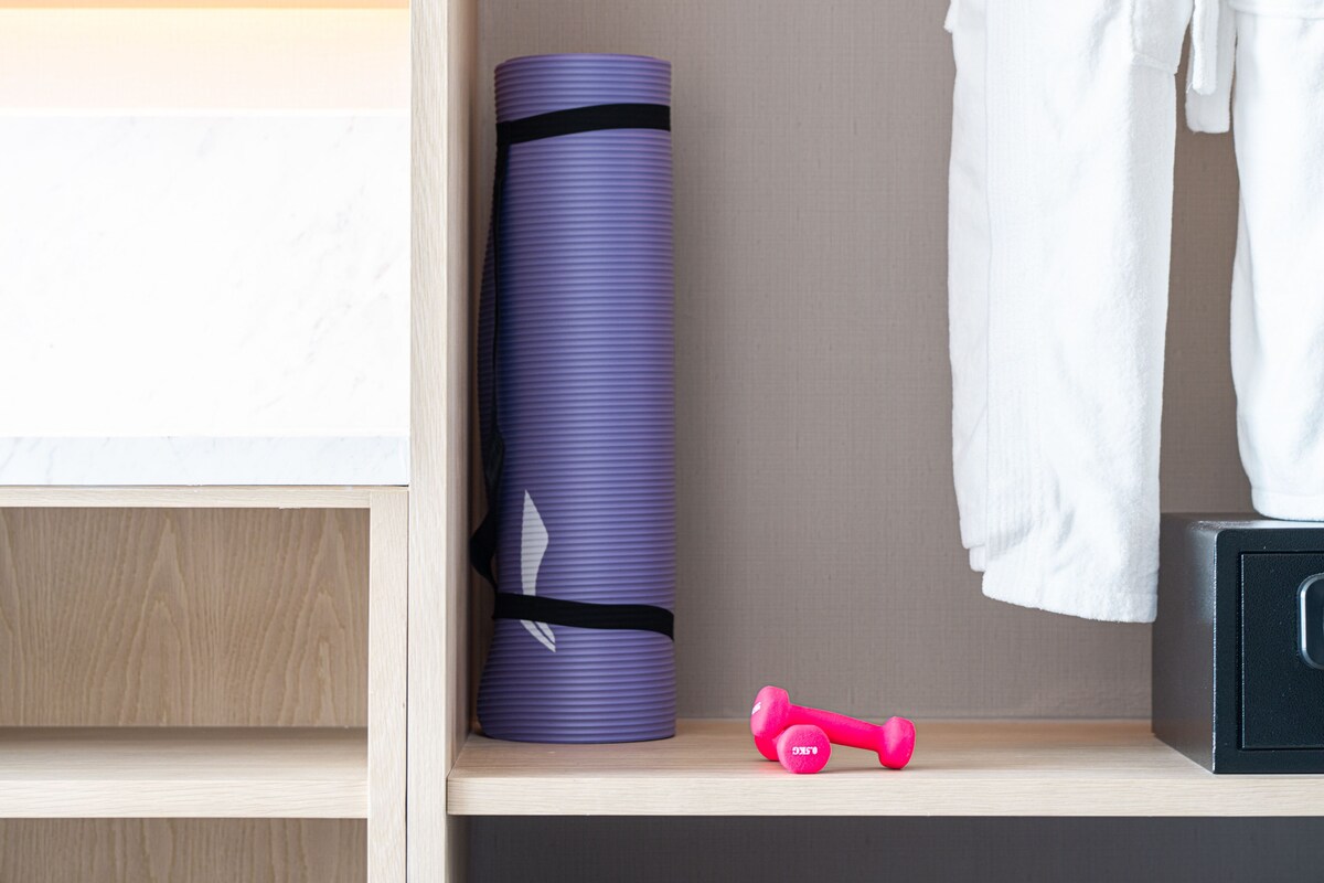 Estante bem organizada com um tapete de yoga roxo, um haltere rosa e uma toalha branca.