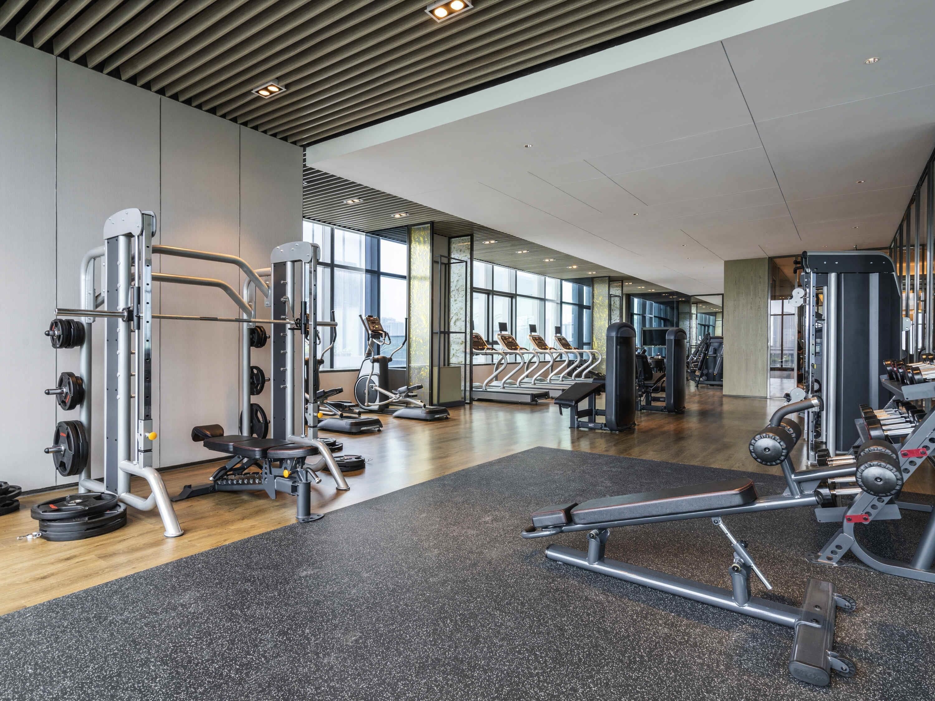 Un gimnasio con diverso equipo de ejercicio, amplias ventanas y un diseño interior moderno.