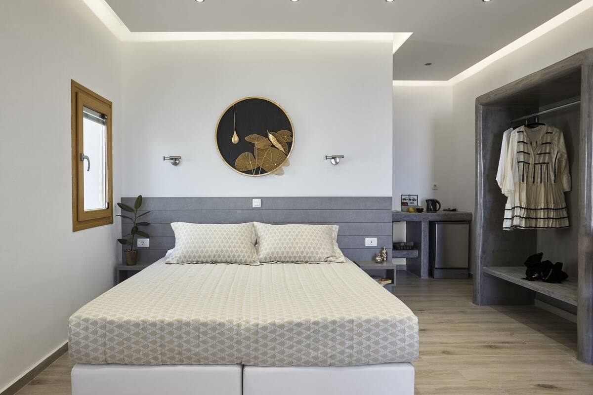 Une chambre moderne avec un grand lit, un élément de décoration circulaire fixé au mur, une armoire et un petit espace bureau.