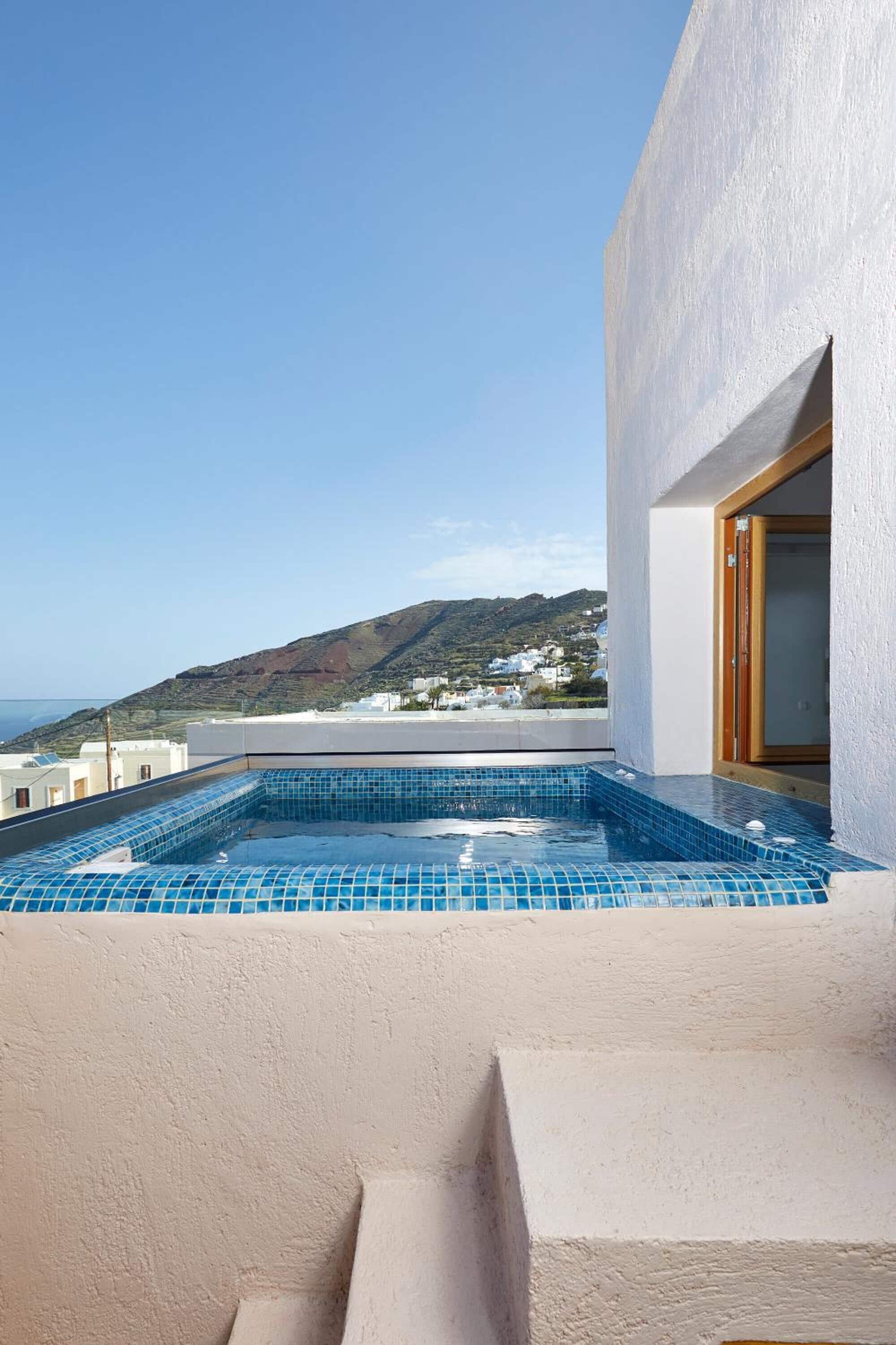 A rooftop pool with a clear view of the sea and hills in the background.