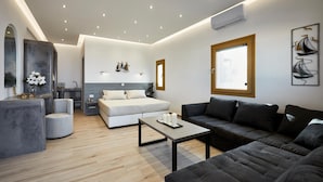 A modern living room with a sofa, a coffee table, a bed, and a small seating area. - Alyvia Suites (Santorini)