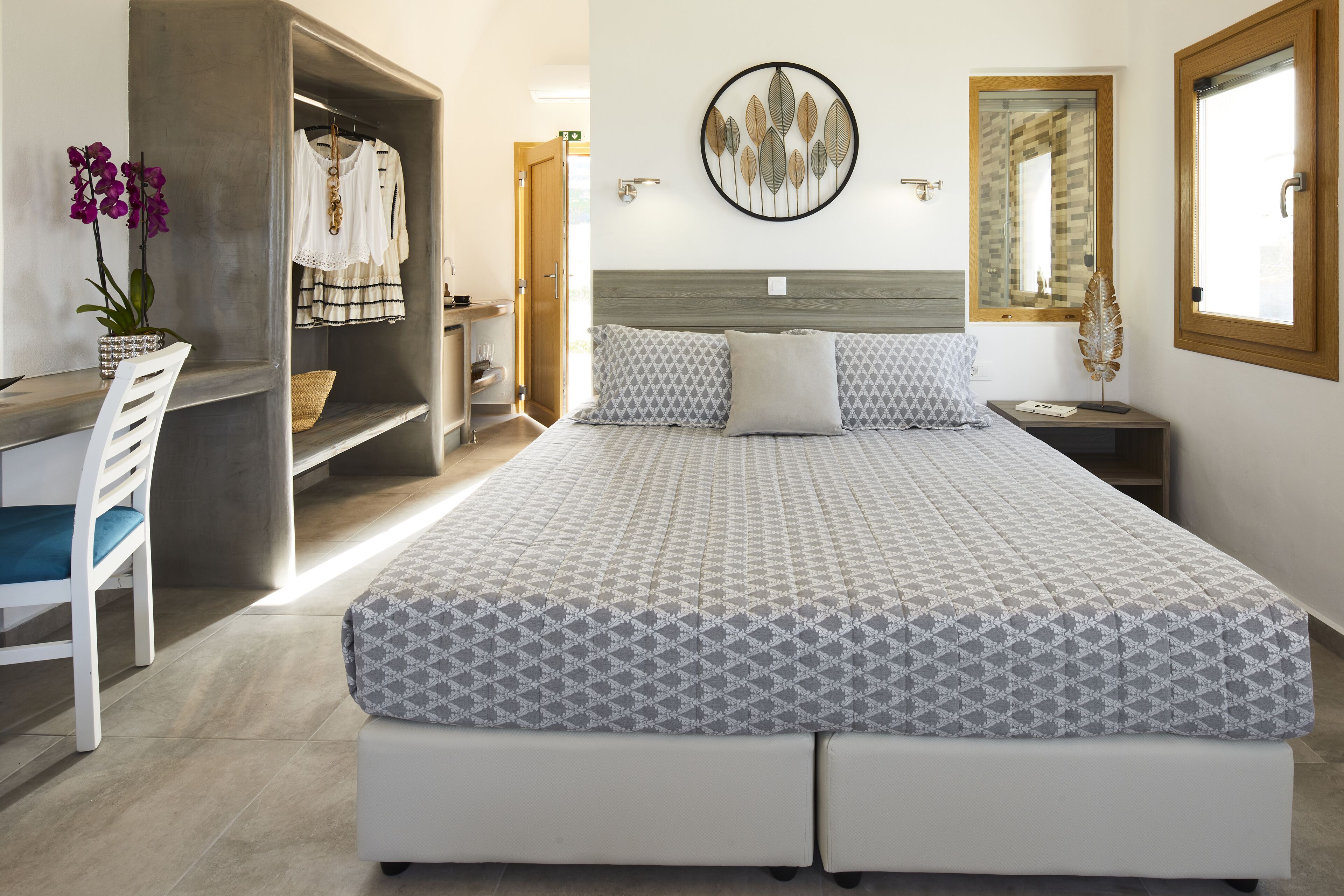 Ein ordentlich eingerichtetes Schlafzimmer mit einem Bett, einem Sessel, einem kleinen Tisch und einem an der Wand befestigten Regal.