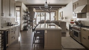 Une cuisine moderne dotée d’un îlot central, de meubles en bois et d’un mur d’accent en pierre.