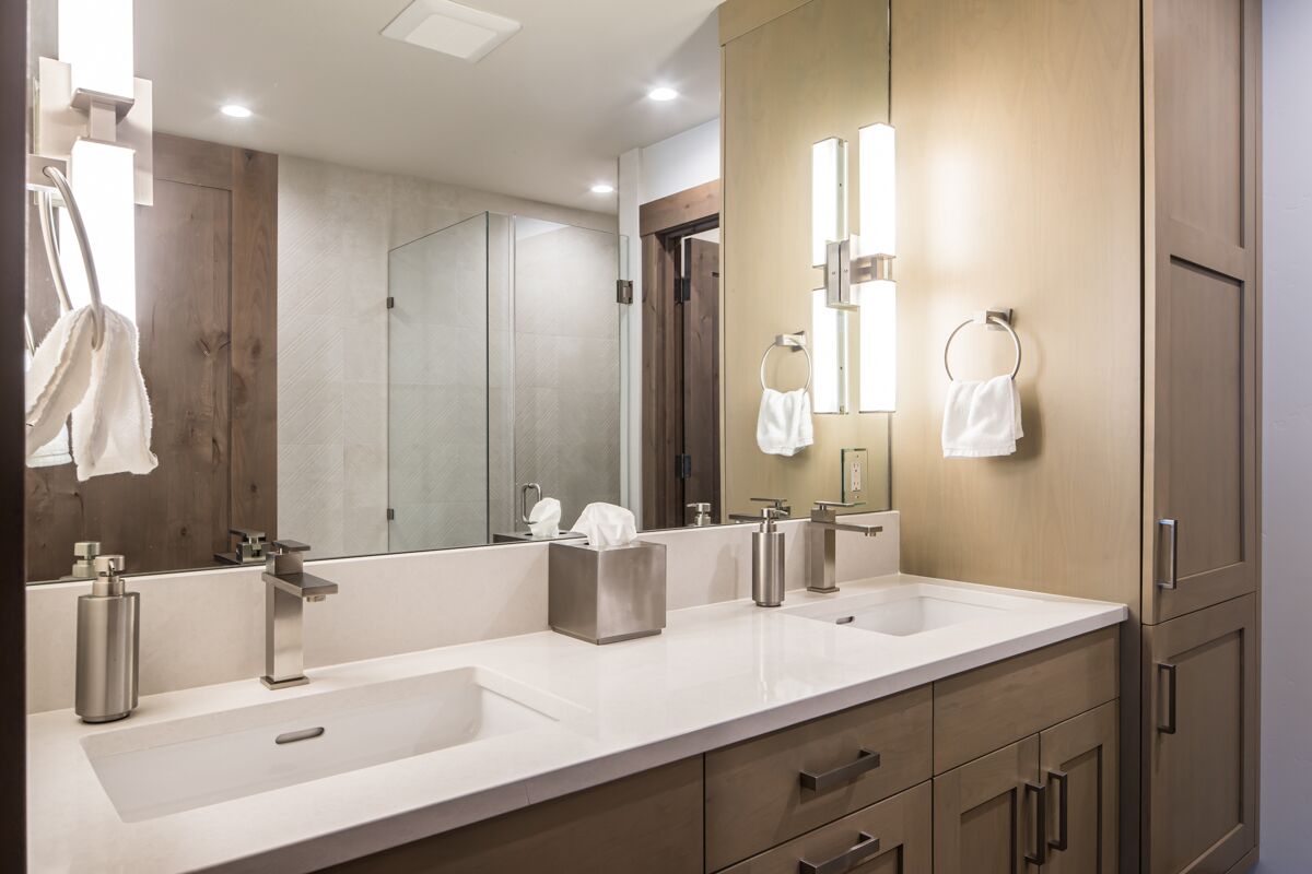 Une salle de bain moderne avec deux lavabos, un grand miroir et des meubles en bois.