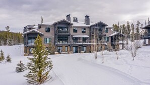 Un immeuble à étages doté d’une architecture moderne, caractérisé par de grandes fenêtres et un paysage enneigé.