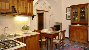 Une cuisine avec des meubles de rangement en bois, une cuisinière à gaz, un évier et une table à manger avec des chaises.