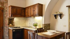 Une cuisine avec des meubles de rangement en bois, une cuisinière à gaz, un évier et une table à manger avec des chaises.