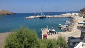 A marina with boats docked, a rocky breakwater, and a building with a balcony overlooking the water. - Casa Tholari Al Mare (Αστυπάλαια)