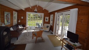 Un chalet confortable doté d’une cheminée, d’un téléviseur et d’un coin repas avec une table et des chaises.