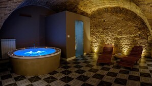 A spa area with a hot tub, wooden benches, and a stone wall. - Marie Claire Apartments Spa (Vasto)