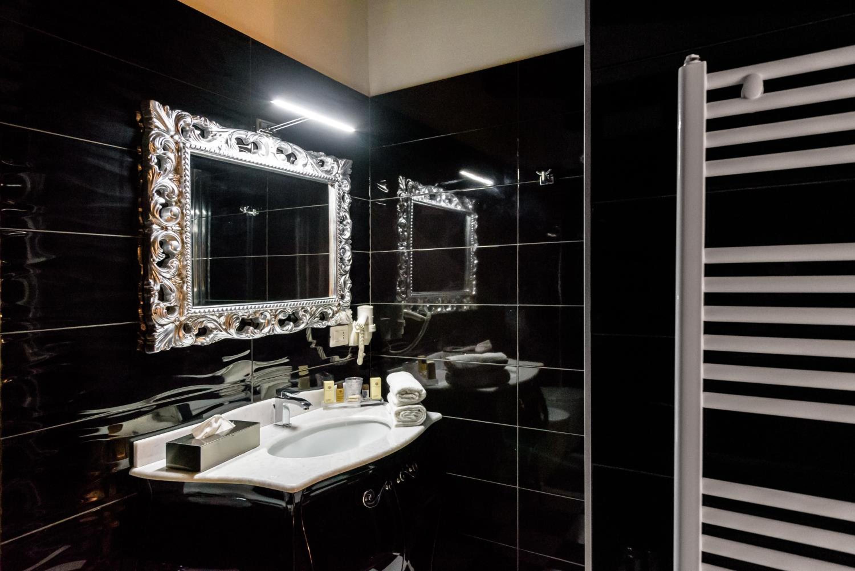 A modern bathroom with a large mirror, a white sink, and a towel rack.