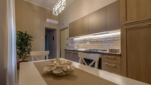 A modern kitchen with a central island, a built-in stove, and a pendant light. - Marie Claire Apartments Spa (Vasto)