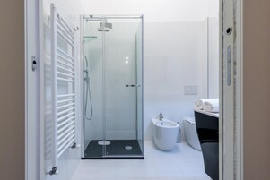 Un bagno moderno con cabina doccia in vetro, un bidet e un water.