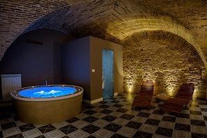 A spa area with a hot tub, wooden benches, and a stone wall.