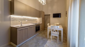 A modern kitchen with a built-in stove, a sink, and a dining area with a table and chairs. - Marie Claire Apartments Spa (Vasto)