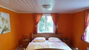 A bedroom with a wooden bed, two nightstands, a window with curtains, and a wall painting.