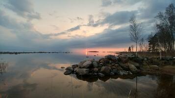 A calm lake with a rocky shoreline and trees in the background.