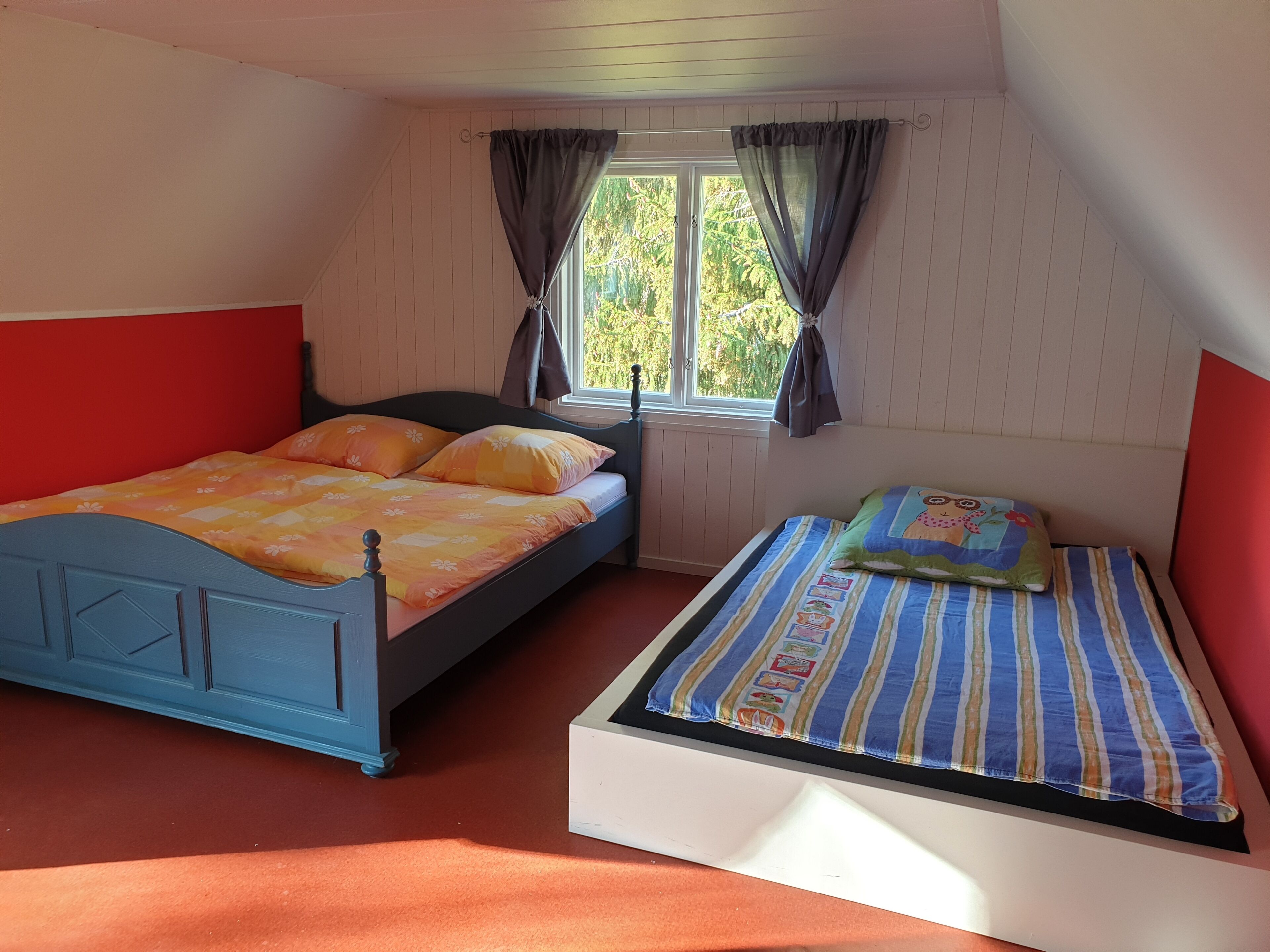 A bedroom with two beds, one blue and one white, with striped bedding.