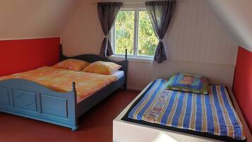 A bedroom with two beds, one blue and one white, with striped bedding.
