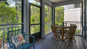 Terraza de madera con mesa y sillas, con vista a un área boscosa.