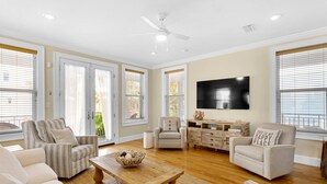 Una sala de estar amplia con un televisor grande, asientos cómodos y un ventilador de techo.