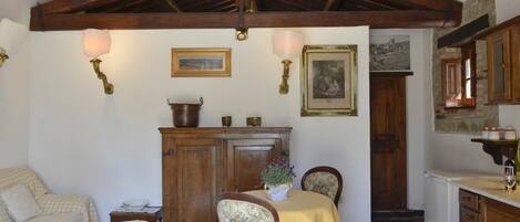 A rustic dining area with a wooden table, chairs, and a chandelier.